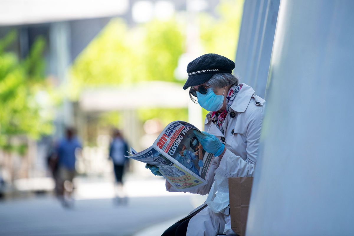 A woman wearing a mask and gloves reads a local newspaper amid the coronavirus pandemic on May 21, 2020 in New York City. (Alexi Rosenfeld/Getty Images)