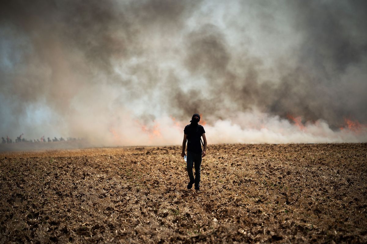 A protester is walking towards a wildfire started by a launched tear gas canister during a march as part of a rally against the construction of a giant water reservoir (mega-bassine) in Migne-Auxances, western France, on July 19, 2024. (Jerome Gilles/NurPhoto via Getty Images)