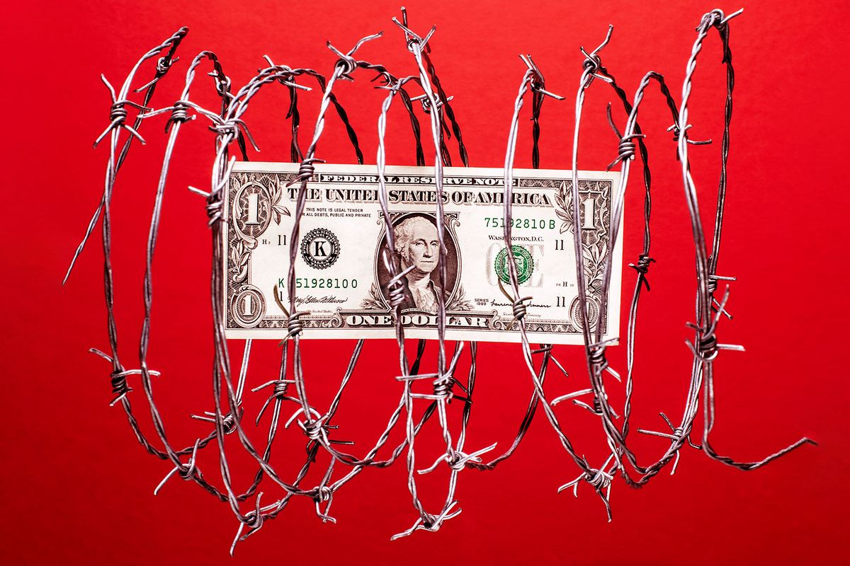 US dollar bill inside coil of steel barbed wire (Getty Images/PM Images)