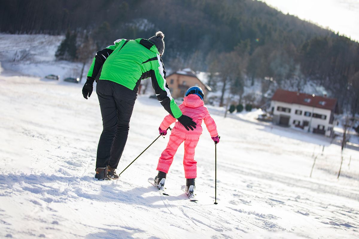 Father Helping Daughter To Learn Skiing (Getty Images/CasarsaGuru)