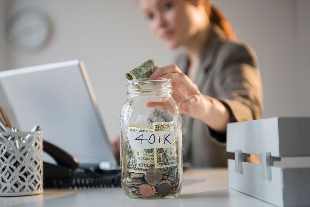 Putting money into a jar labeled "401K" (Getty Images/Jamie Grill)