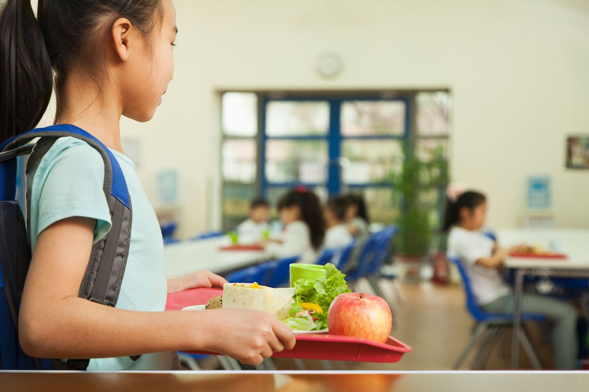 School girl holding food tray in school cafeteria (Getty Images/XiXinXing)