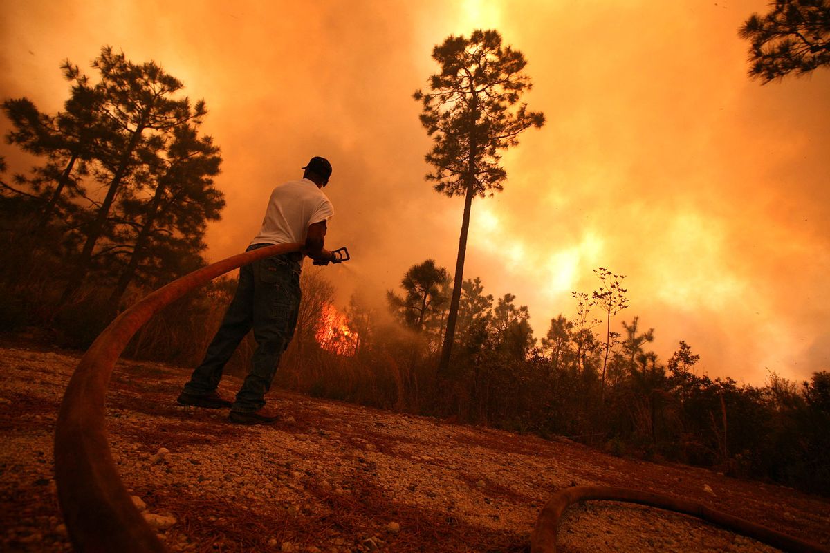 A man sprays water on a raging fire as it threatens nearby homes on April 23, 2009 near Conway, South Carolina. (Logan Mock-Bunting/Getty Images)