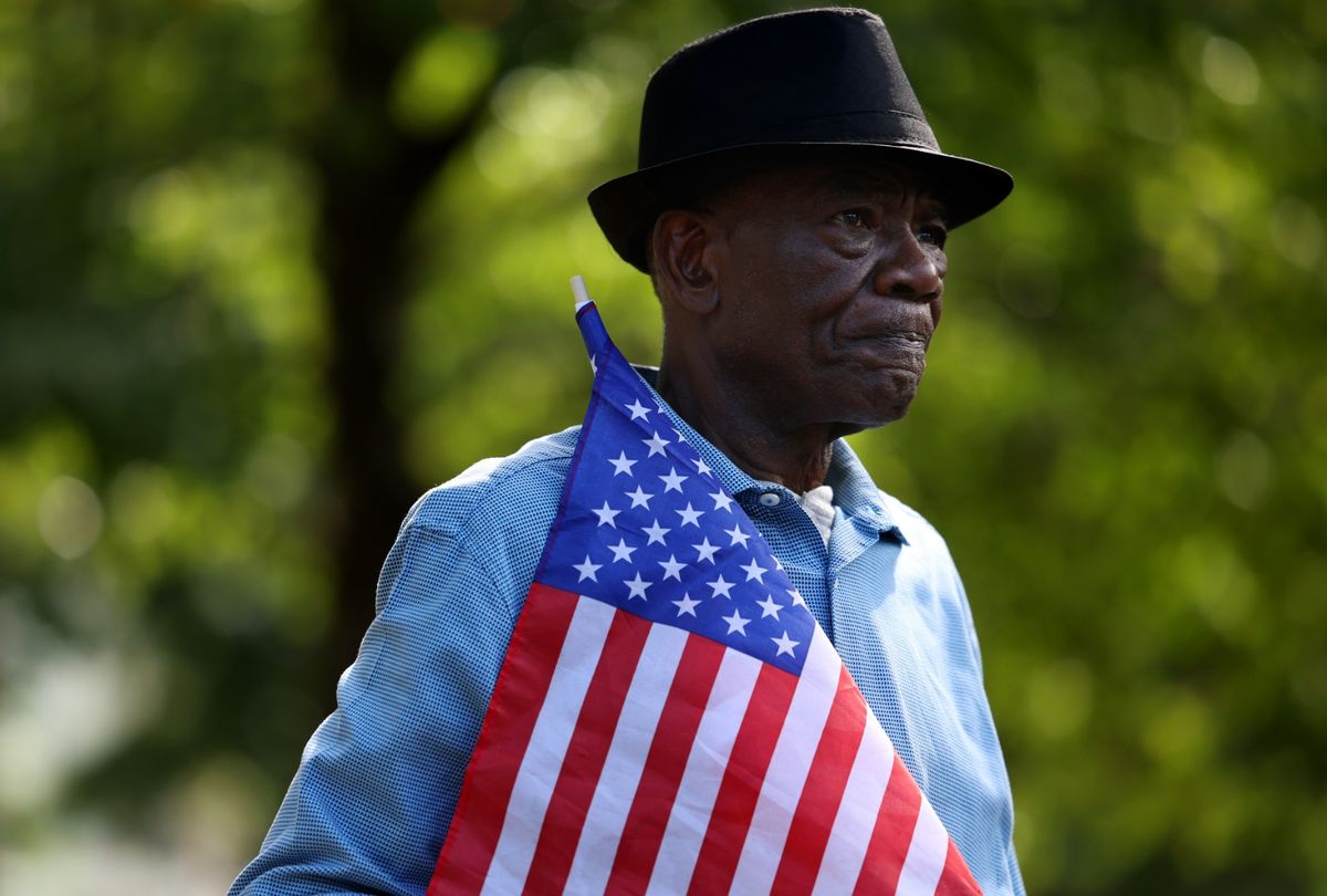 A man held an American flag as he and other members of the Haitian community gathered to denounce the hateful rhetoric aimed towards Haitian migrants in Ohio. (Jessica Rinaldi/The Boston Globe via Getty Images)