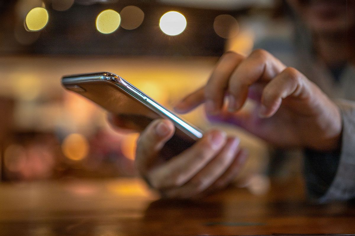 Man Holding their phone (Getty Images/boonchai wedmakawand)