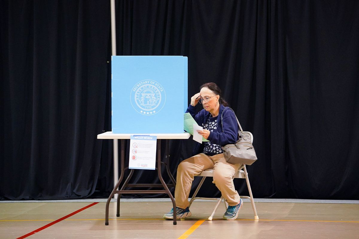 A woman reads a piece of paper while visiting a polling place to cast her ballot on November 5, 2024 in Smyrna, Georgia. (Megan Varner/Getty Images)