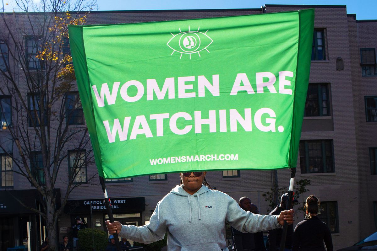 An abortion rights activist holding a sign with Women are Waching is written on it, gathers in front of the Heritage Foundation during the Women's March on November 09, 2024. (Probal Rashid/LightRocket via Getty Images)