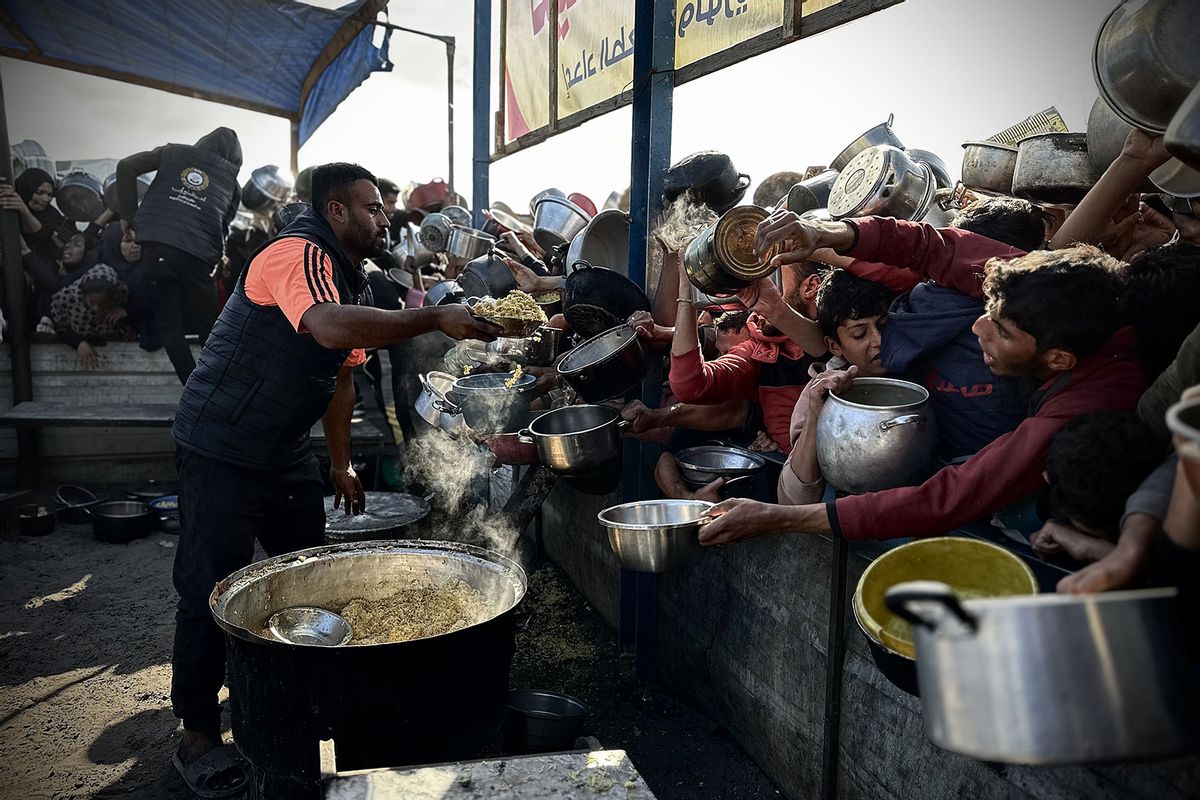 Palestinians, carrying empty pots, line up to receive meals, distributed by charity organizations, as people struggle with hunger due to embargo imposed by Israeli forces in Khan Yunis, Gaza on December 13, 2024. (Doaa Albaz/Anadolu via Getty Images)