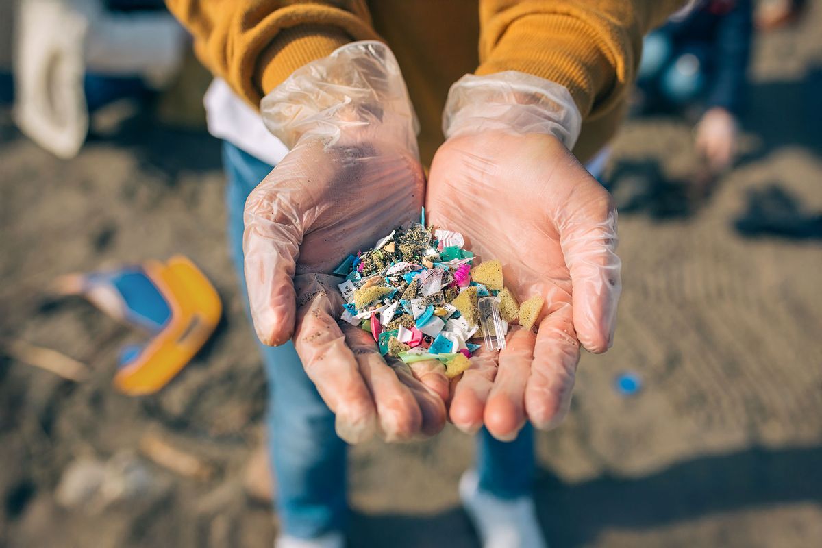 Hands holding microplastics on the beach (Getty Images/doble-d)