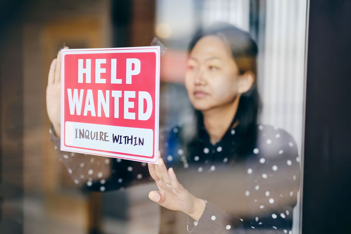 Business Owner Putting Up Help Wanted Sign (Getty Images/RichLegg)