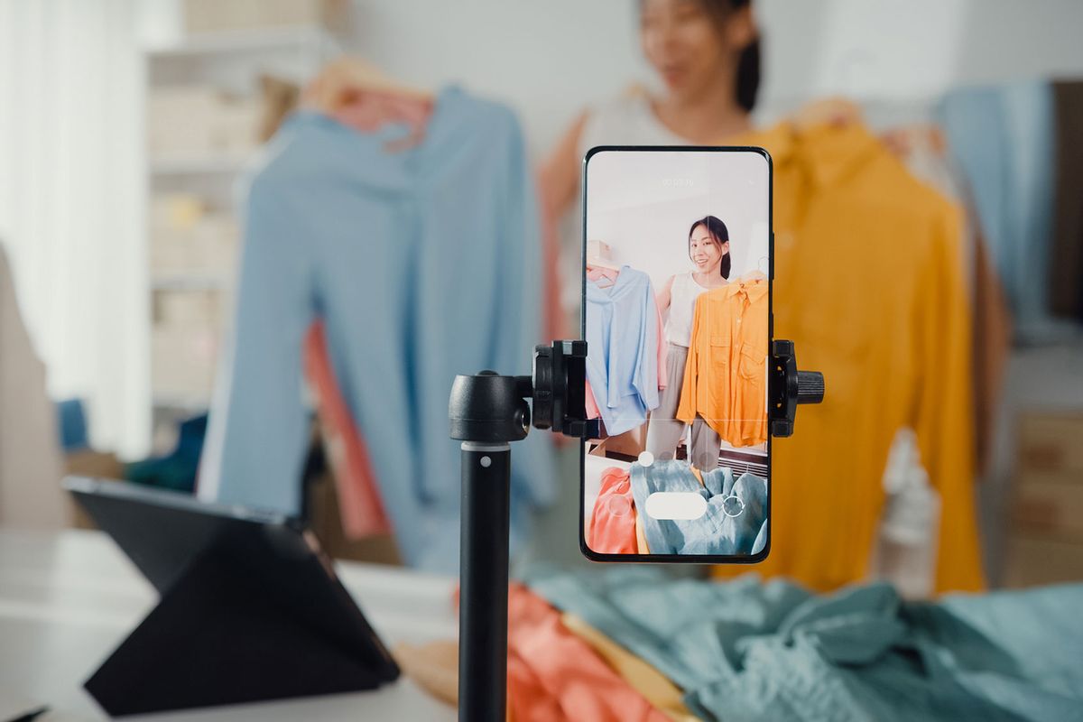 Businesswoman live-streamed e-commerce clothing sale at home (Getty Images/MTStock Studio)