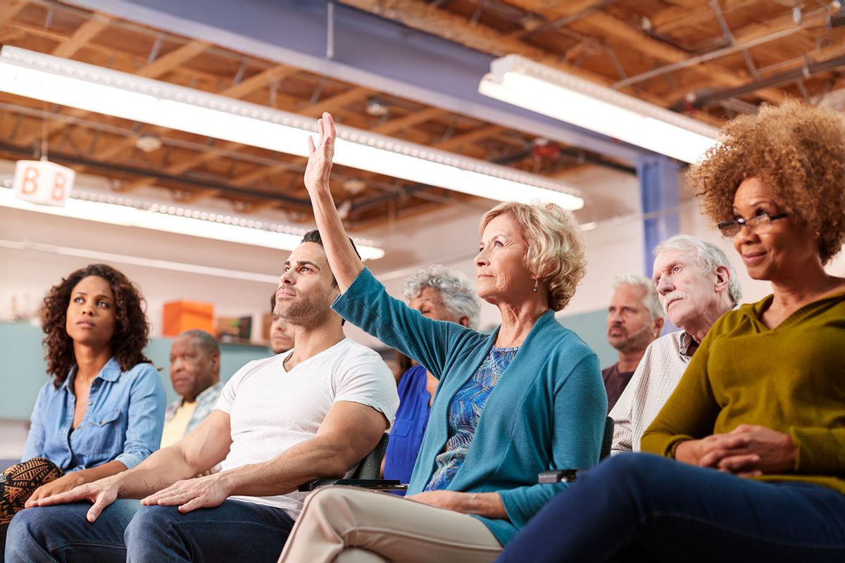Woman Asking Question At Neighborhood Meeting (Getty Images/monkeybusinessimages)