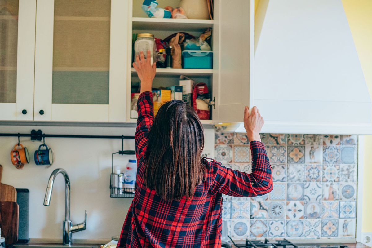 A young woman reaching for ingredients in the kitchen pantry (Getty Images/VioletaStoimenova)