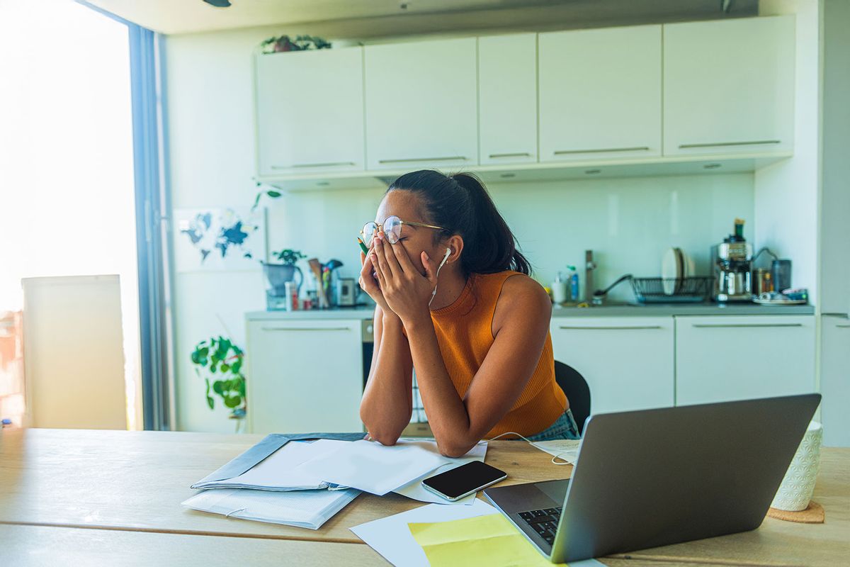 A busy young woman doing paperwork from home (Getty Images/DRAKULA IMAGES)