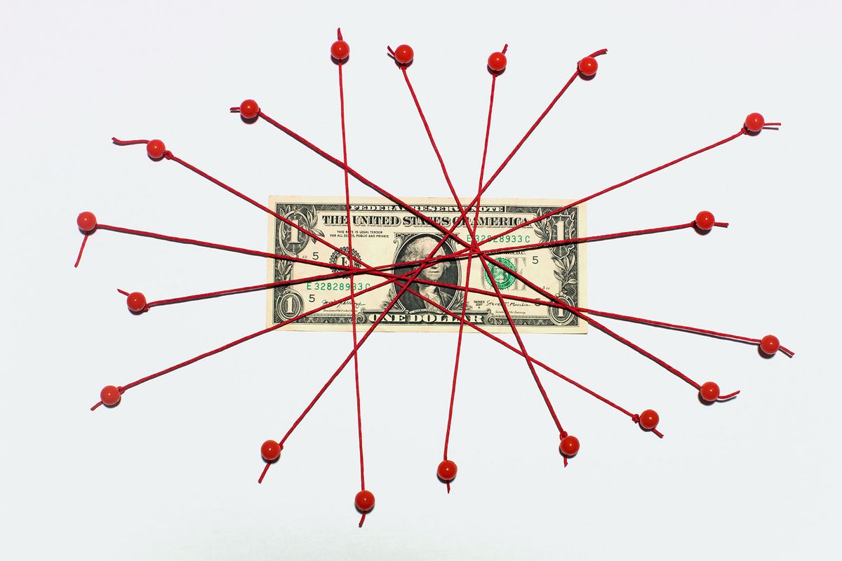 One US $1 bill tied down with bright red string and red thumb tacks (Getty Images/PM Images)
