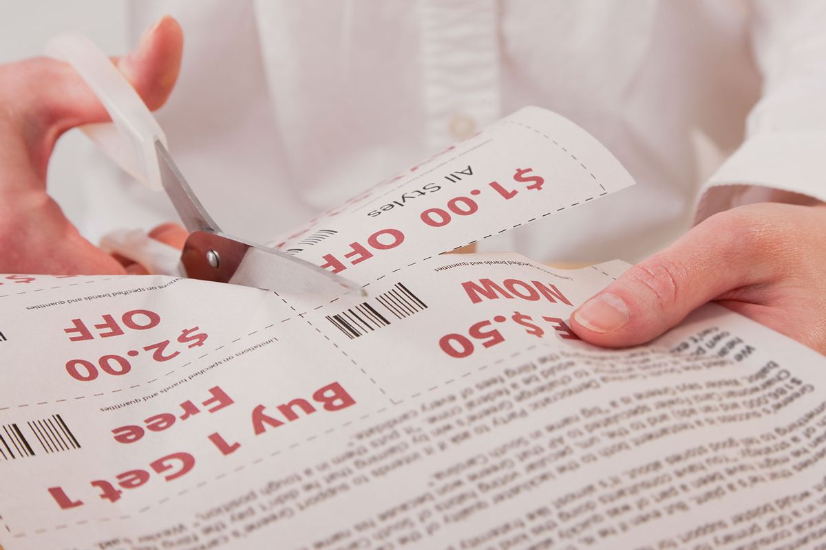 Person cutting out shopping coupon (Getty Images/Vstock LLC)