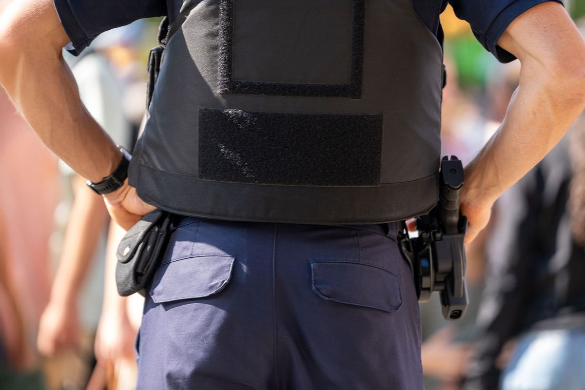Police officer with a gun holstered at a public event (Getty Images/Roman Studio)