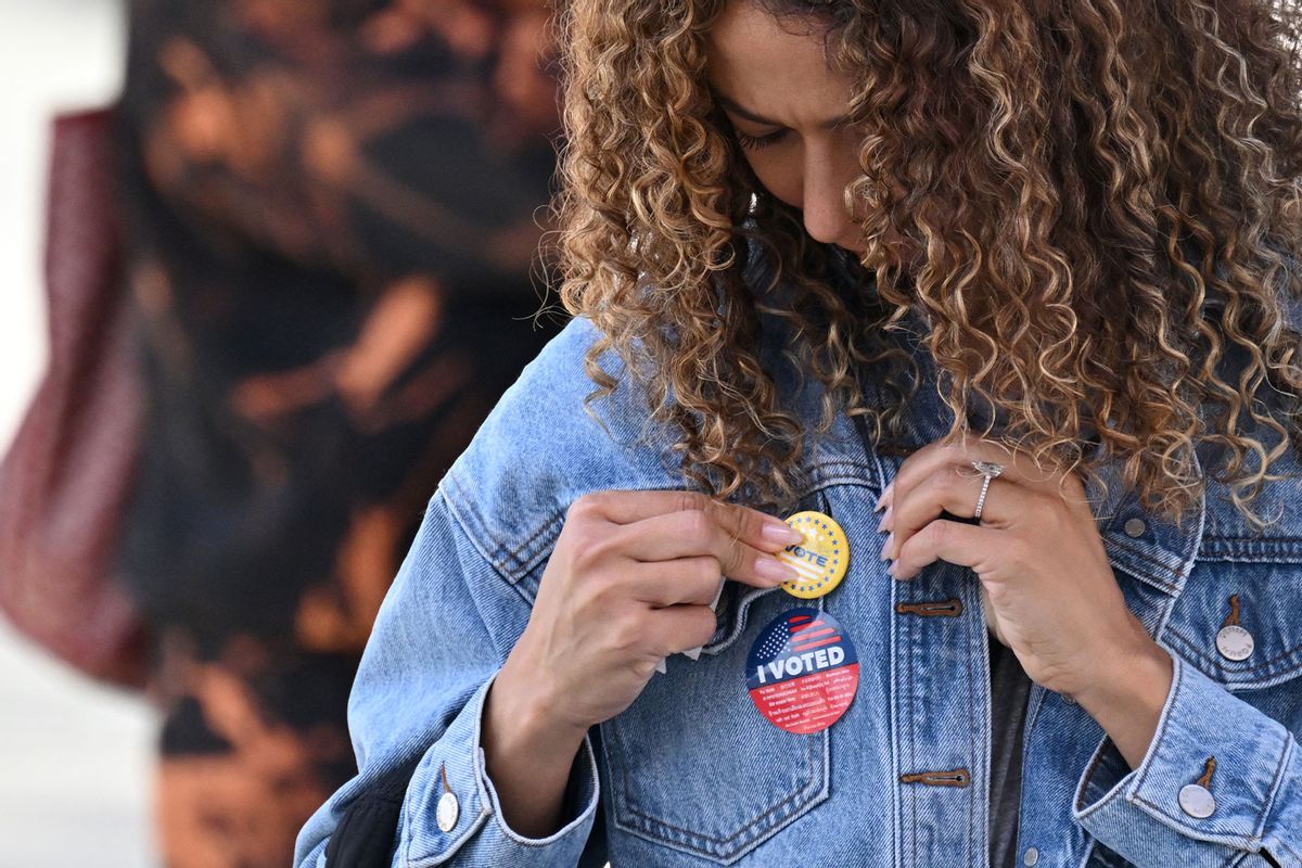 A young woman attaches a pin to her jacket after voting at a mobile outdoor vote center at SoFi Stadium in Los Angeles, California, on Election Day, November 5, 2024. (ROBYN BECK/AFP via Getty Images)