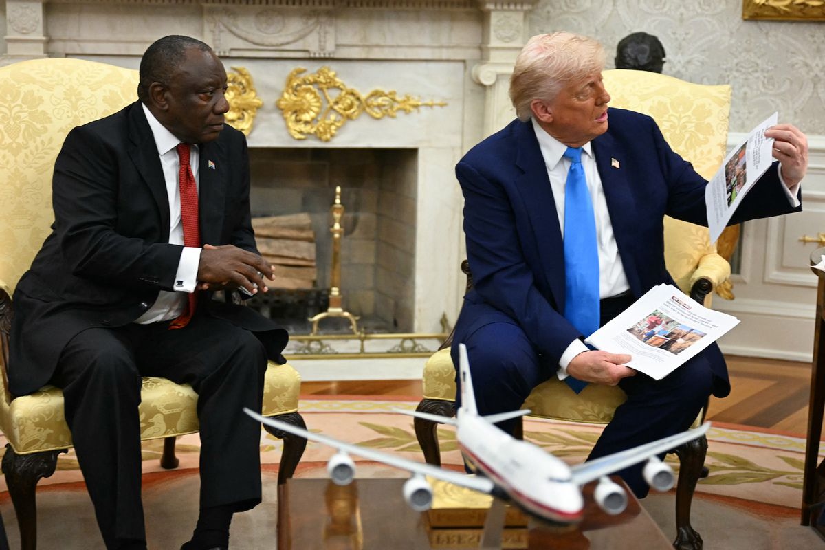 US President Donald Trump shows pictures and articles as he meets with South African President Cyril Ramaphosa in the Oval Office of the White House in Washington, DC, on May 21, 2025. South African President Cyril Ramaphosa meets Donald Trump on Wednesday amid tensions over Washington's resettlement of white Afrikaners that the US president claims are the victims of "genocide."  (Photo by Jim Watson/Getty Images)