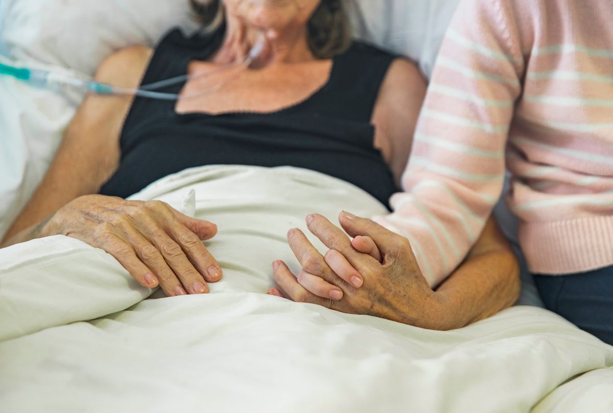 Young girl holds the hand of her ill grandmother. (Getty Images / Justin Paget)