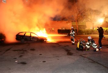 Firefighters extinguish a burning car in the Stockholm suburb of Kista