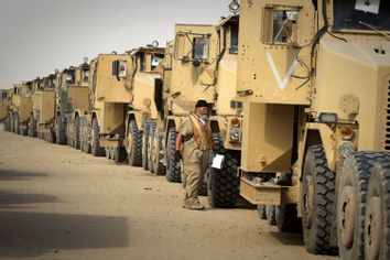 A contractor walks between trucks returned from Iraq to Camp Arafjan in Kuwait