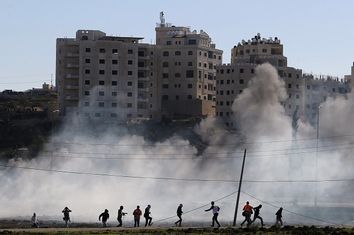 Palestinian protesters run away from tear gas fired by Israeli troops during clashes near Ramallah
