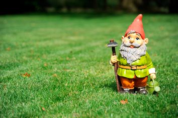 Close-up of garden gnome holding pickax and watering can