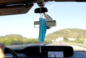 Protective mask hanging on a rearview mirror 
