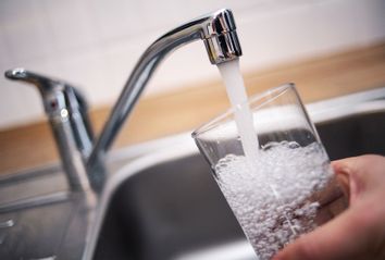 A man holds a glass under a running tap