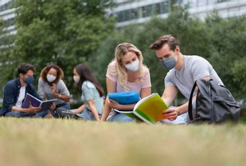 Students wearing face masks while studying outdoors