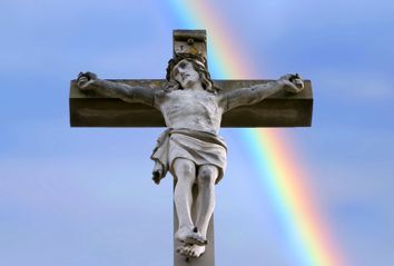 Rainbow behind a stone cross with Jesus