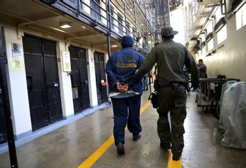 An armed California Department of Corrections and Rehabilitation (CDCR) officer escorts a condemned inamte at San Quentin State Prison's death row