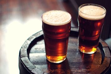 Two pints of beer bitter on wooden barrel in pub