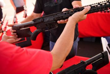 A clerk hands a customer a California legal, featureless AR-15 style rifle.