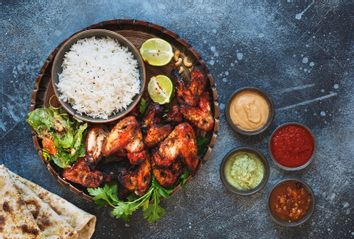 Tandoori chicken wings served with pilau rice, soft garlic cheese naan with different chutney dipping sauces
