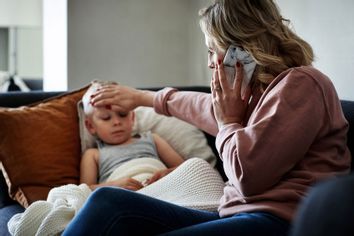Mother making a phone call while aiding to her sick young son at home