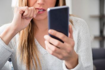Nervous young woman using smartphone