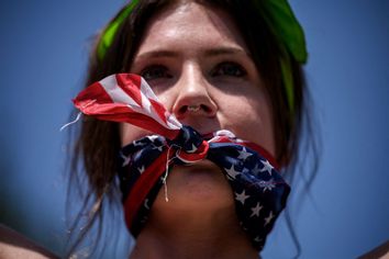 A reproductive rights activist, gagged by a scarf in the colors of the US flag