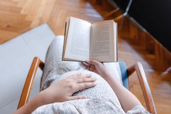 Pregnant Woman Touching Her Belly While Reading a Book