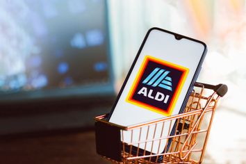 An Aldi logo seen displayed on a smartphone along with a shopping cart.