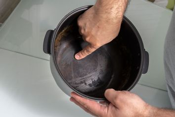 A man holding a non-stick pan with a damaged coating