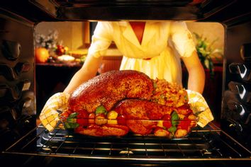 Woman preparing roasted turkey in oven