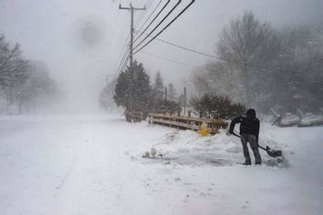 A man shovels snow in near whiteout conditions during a noreaster