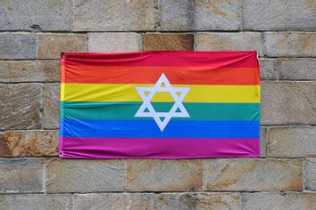 Gay pride rainbow flag with Star of David, pinned to a stone wall