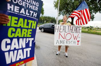 Supporters of the health care reform hold signs outside a health care town hall meeting with U.S. congressman Kendrick Meeks (R-FL) in Miami