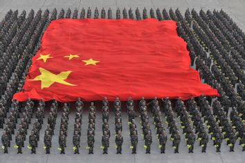 Paramilitary policemen hold a Chinese national flag during a parade training session at a military base on the outskirts of Beijing