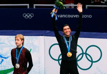Gold medallist Lysacek of the U.S. waves as he stands next to silver medallist Plushenko of Russia during the medal ceremony in Vancouver