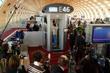 A security official prepares to scan a man posing inside a full-body scanner being trialled by Roissy Charles-de-Gaulle airport