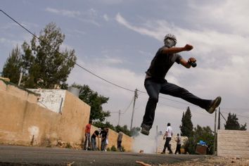 Palestinian throws a stone towards Israeli border police during clashes near Ramallah